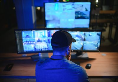 Security operator controls CCTV cameras in office at night. Modern security system and social safety concept.